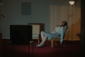 A woman leans back against a chair.