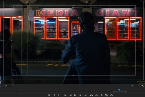 On a computer editing screen, a man stands in front of a video store.