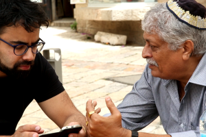 An older man in a yarmulka speaks with younger bearded man.  