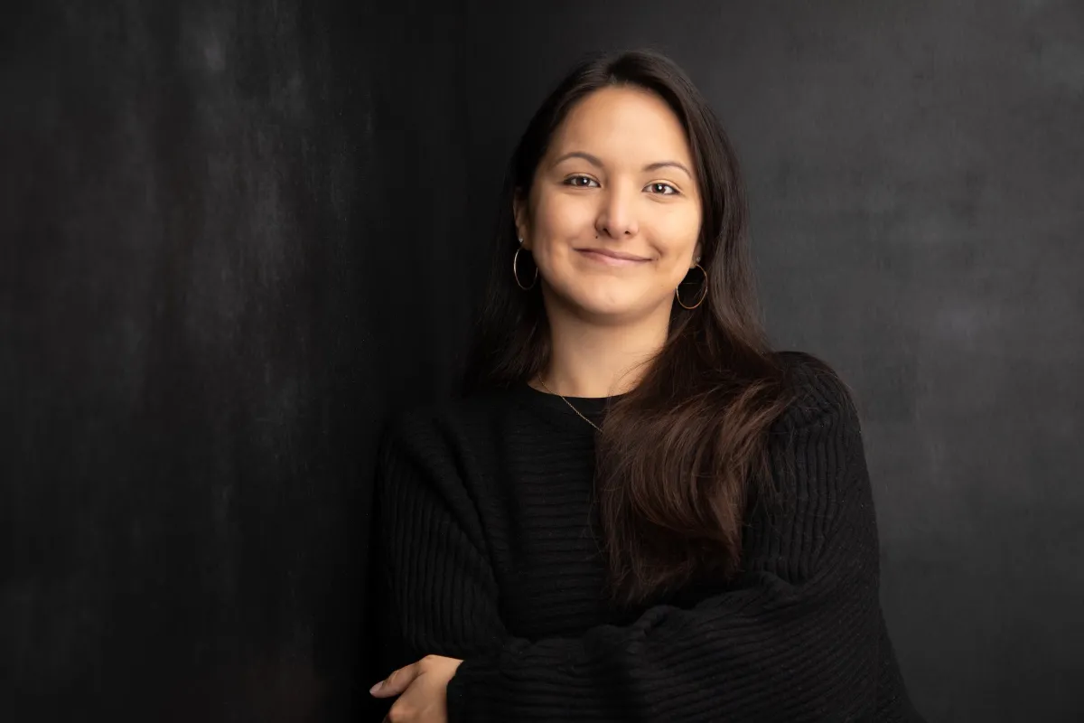 Headshot photograph of Erin Lau, a Native Hawaiian filmmaker with shoulder-length black hair, wearing a black shirt in front of a dark backdrop.